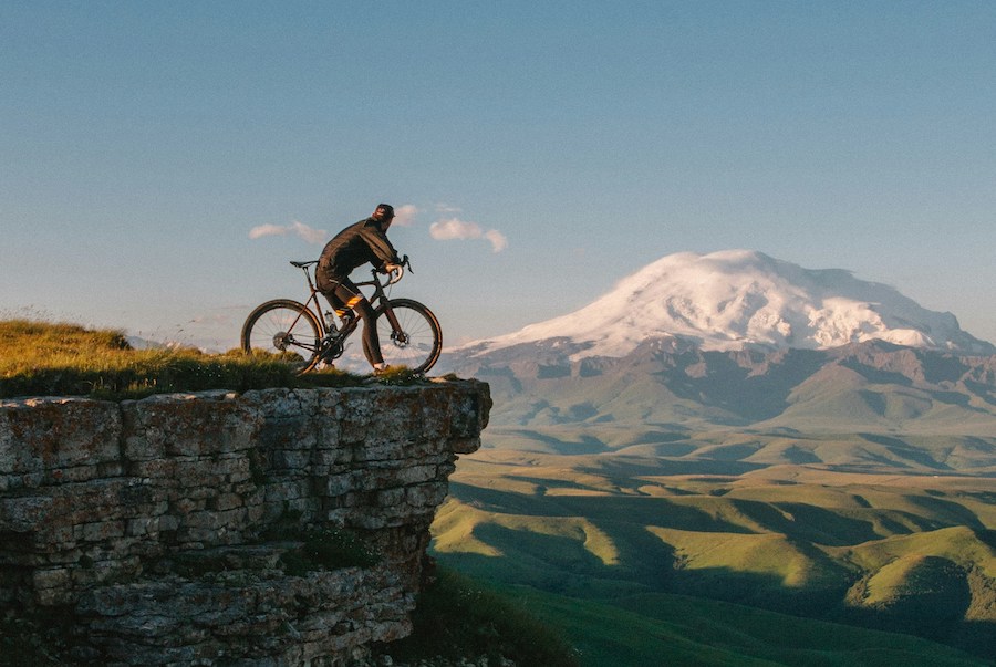 Homem encima da bicicleta no topo de uma montanha