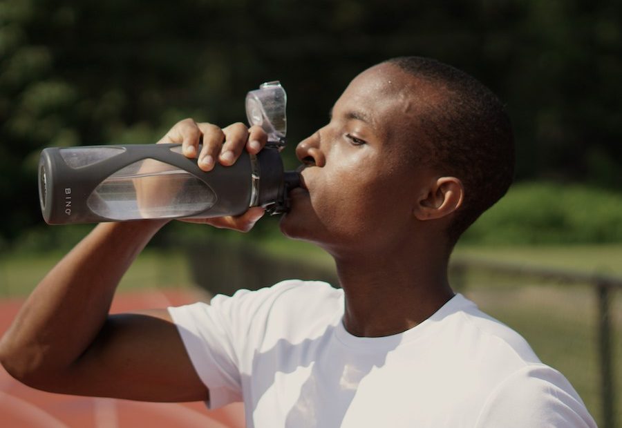 Homem bebendo agua em uma pista de atletismo