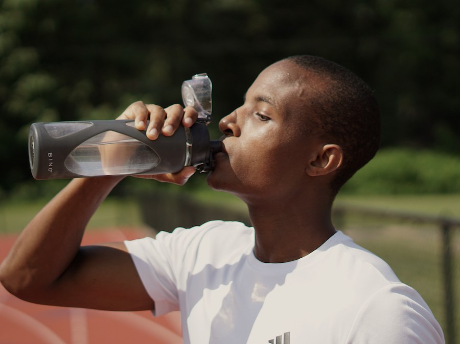 Homem bebendo agua em uma pista de atletismo